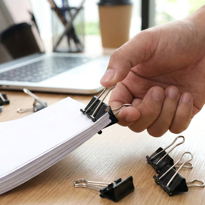 Black metal binder clips holding sheets of paper tightly