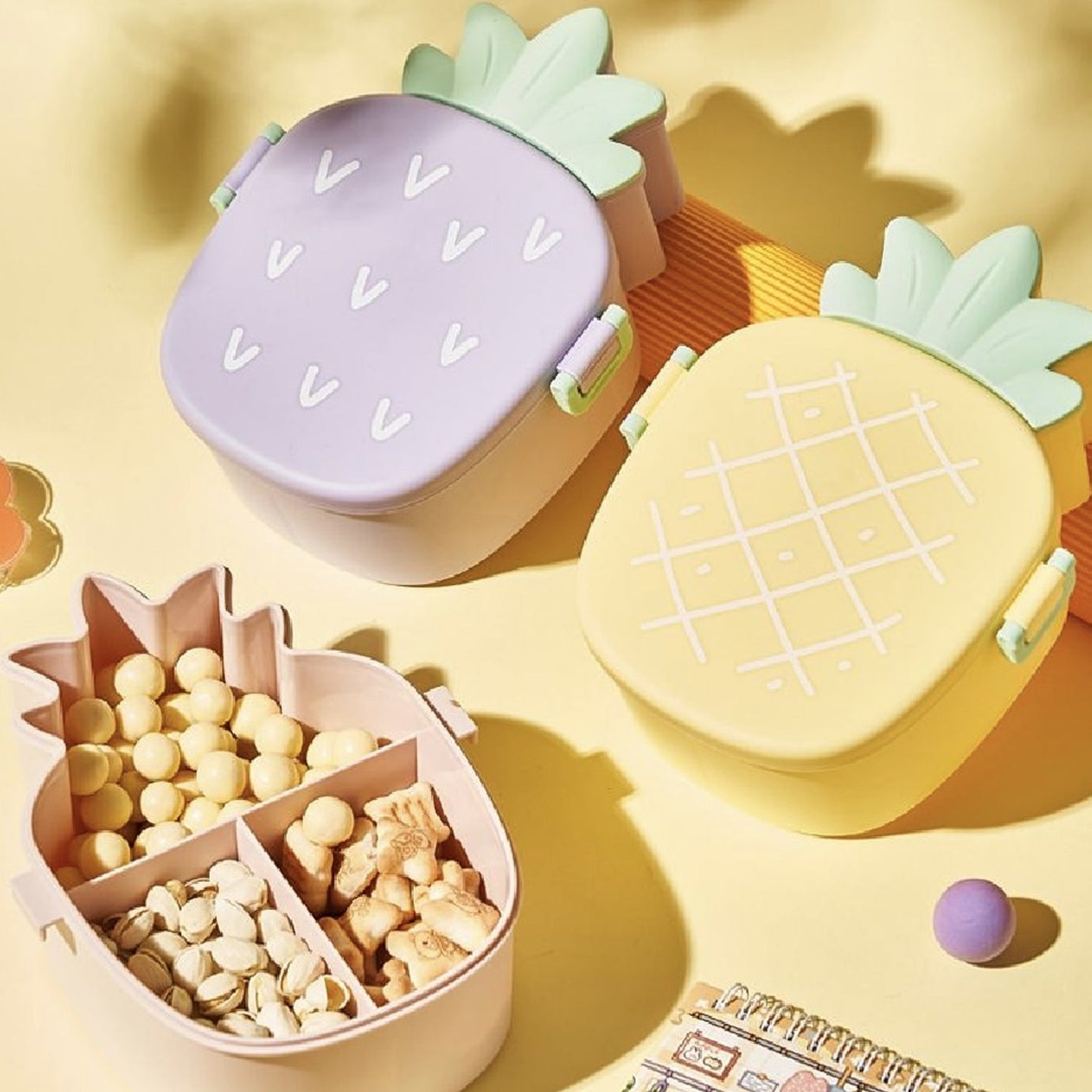 Open pineapple kids bento lunch box showing separate compartments, a fork, and a spoon.